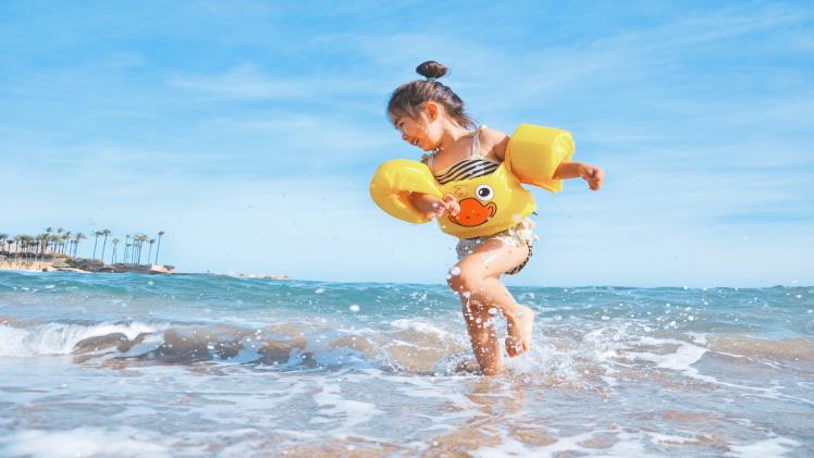 A picture of a little girl playing in the ocean on vacation with her family and Royal Holiday Vacation Club.